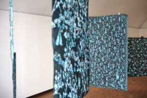 Im Raum hängende große Bilder mit blau-schwarzer Farbgebung 